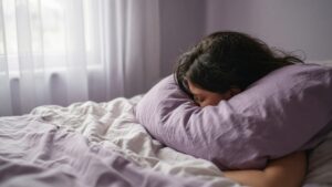 Young woman sleeping peacefully in soft lavender bedding in gentle morning light